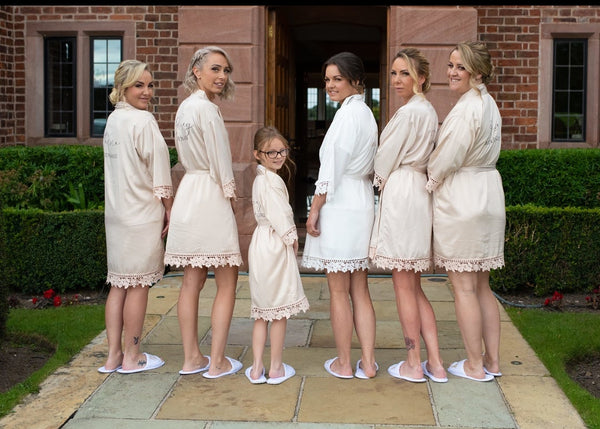 Group of women and a child in white robes standing on a patio.