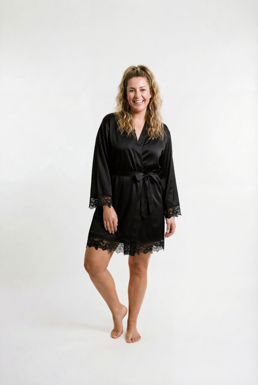 Woman wearing a black satin robe with lace trim on a white background