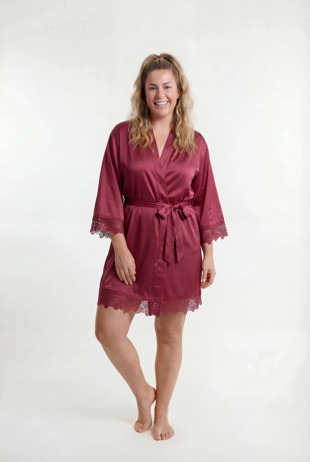 Woman wearing a burgundy robe with lace trim on a white background