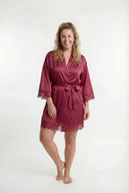 Woman wearing a burgundy robe with lace trim on a white background