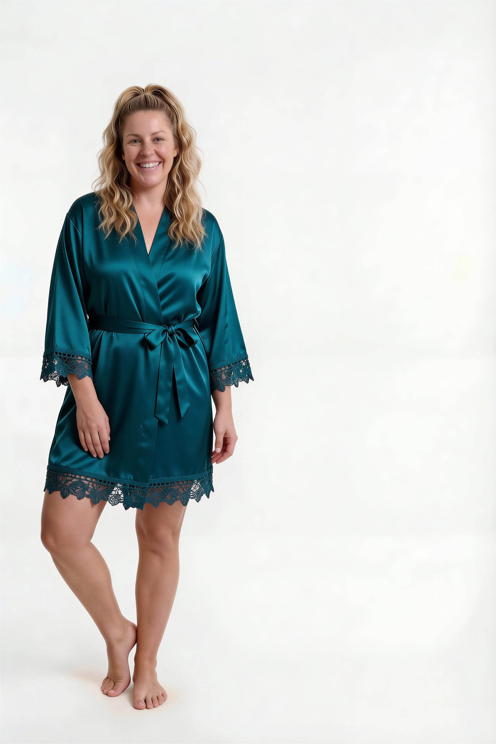 Woman wearing a teal satin robe with lace trim on a white background